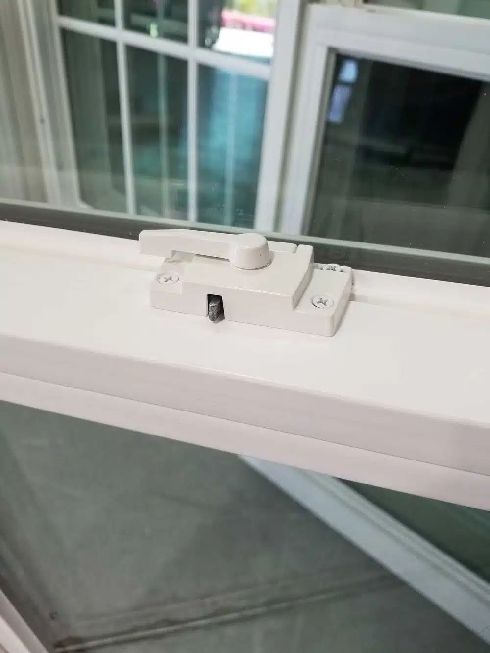 Close-up of a cam lock with an integrated safety latch on a secure home window.